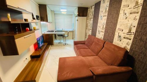 a living room with a brown couch and a kitchen at Apartament modern -mobilat nou in Chiajna