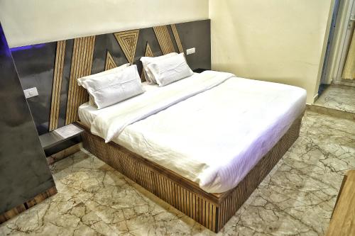 een bed met witte lakens en kussens in een kamer bij Hotel Aaryan Comforts - Peenya in Bangalore