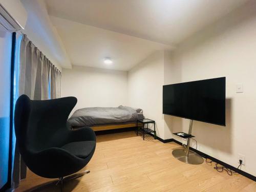 a living room with a chair and a television at home shinjuku west301 in Tokyo