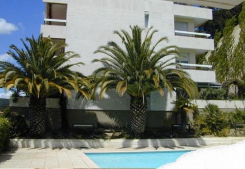 two palm trees in front of a building with a swimming pool at STUDIO LA PINTA CASSIS in Cassis