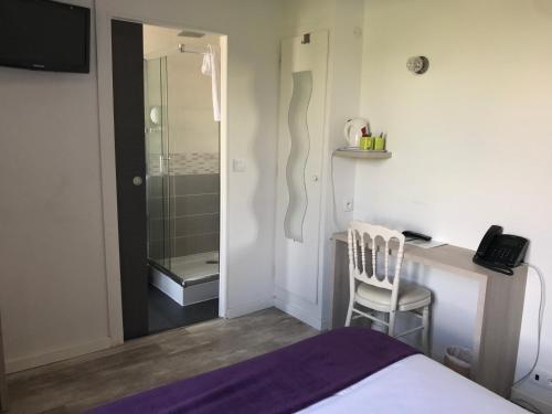 a bedroom with a bed and a desk with a phone at Logis - Hôtel & Restaurant Moulin Des Forges in Saint-Omer-en-Chaussée
