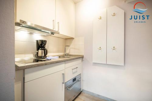 a kitchen with white cabinets and a sink at Haus Inselresidenz Strandburg 312 - Wohnung 112 in Juist