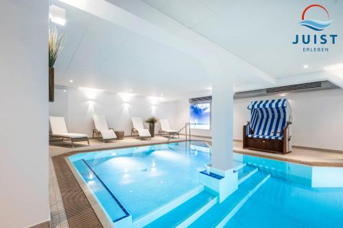 a pool in a hotel room with chairs and a pool at Haus Inselresidenz Strandburg 312 - Wohnung 112 in Juist