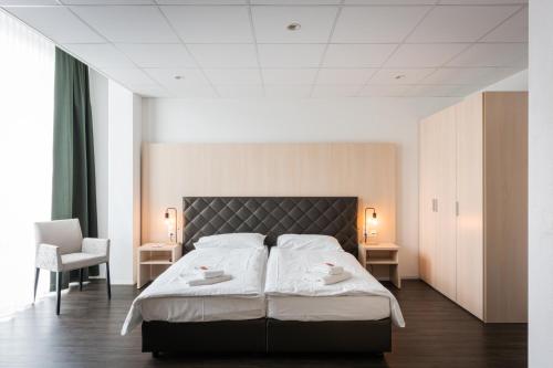una camera da letto con un grande letto con due asciugamani bianchi di Los Lorentes Aparthotel Bern Airport a Belp
