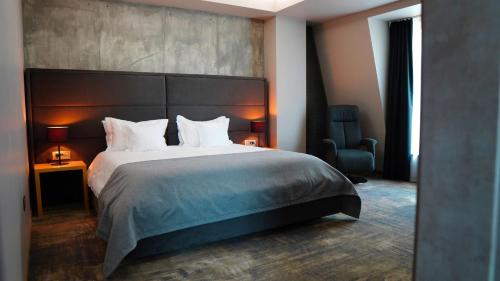 a bedroom with a large bed and a chair at Aniroc Signature Hotel in Arad