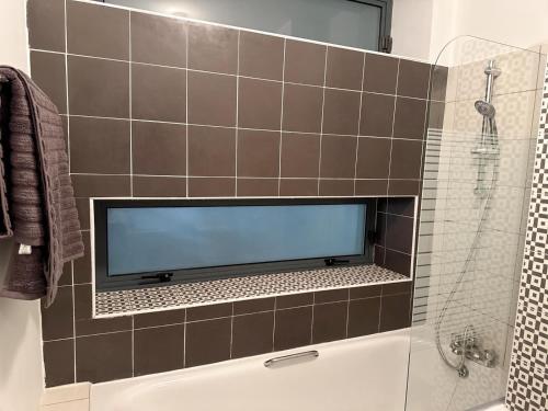 ein Bad mit einem Flachbild-TV an einer gefliesten Wand in der Unterkunft Dallkey Retreat in Dalkey