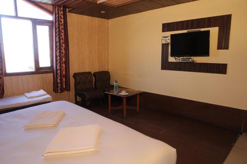 a room with a bed and a tv on the wall at Hotel Sita Inn in Shimla