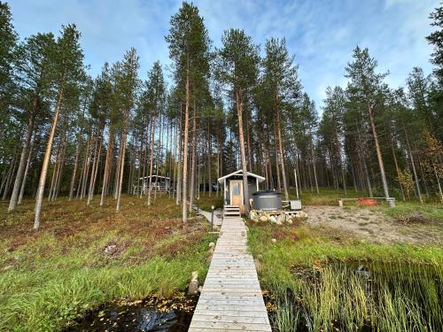 a wooden boardwalk leading to a cabin in the woods at Kenttäpirtti in Kittilä