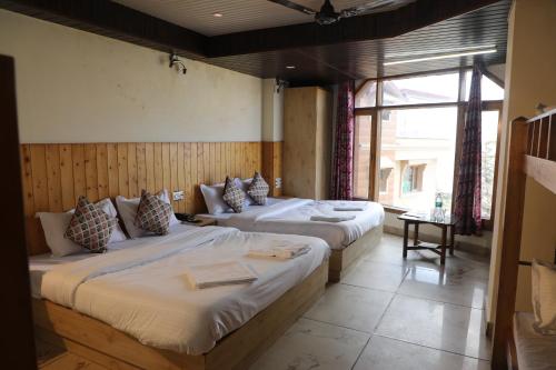 a bedroom with two beds and a large window at Hotel Sita Inn in Shimla