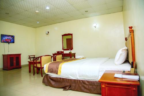 a bedroom with a bed and a table and a mirror at Classicus Inn & Apartments in Ibadan