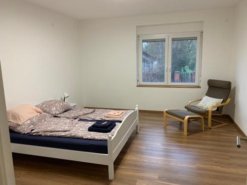 a bedroom with a bed and a chair and a window at Sárdoár Vendégház in Abádszalók