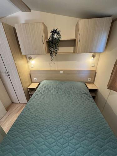 une chambre avec un grand lit avec une couverture verte dans l'établissement Mobilhome 3 chambres 6 personnes près de la plage - Novela - Frédéric et Sandra, à Port-la-Nouvelle