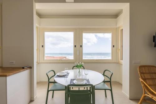 a dining room with a table and chairs and a window at Effe's apartment- ARYA seaview -parcheggio gratuito in Alassio