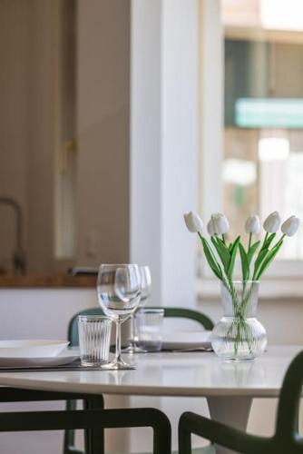 a table with two glasses and a vase with white flowers at Effe's apartment- ARYA seaview -parcheggio gratuito in Alassio