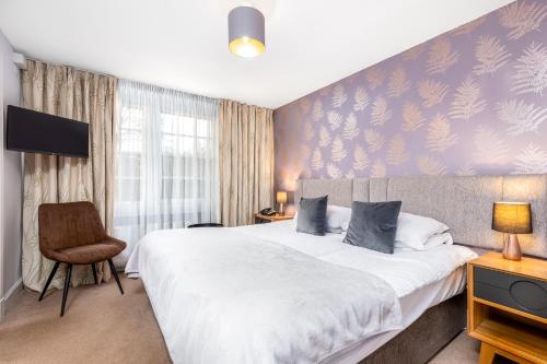 a bedroom with a large bed and a chair at Dornoch Castle Hotel in Dornoch