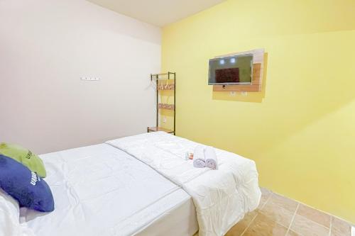 a bedroom with a bed with white sheets and a tv at Urbanview Hotel Sany Cirebon in Tangkil
