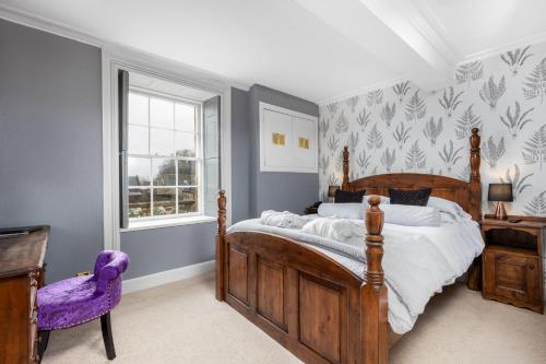 a bedroom with a wooden bed and a purple chair at Dornoch Castle Hotel in Dornoch
