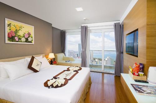 ニャチャンにあるデンドロ ゴールド ホテルのベッドと大きな窓が備わるホテルルームです。