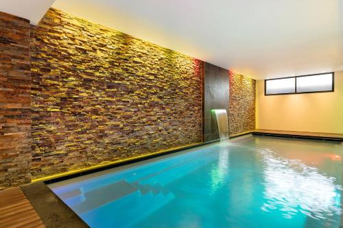 una piscina en una habitación con una pared de ladrillo en Corendon Amsterdam New-West, a Tribute Portfolio Hotel, en Ámsterdam