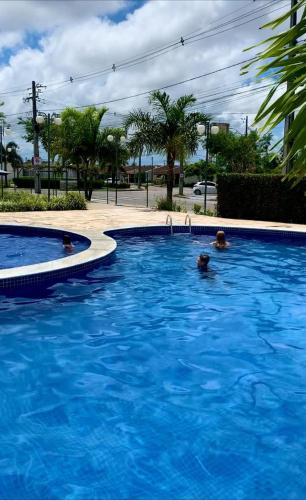2 personas nadando en una gran piscina azul en Casa Aeroporto Maceió Palmeiras en Maceió