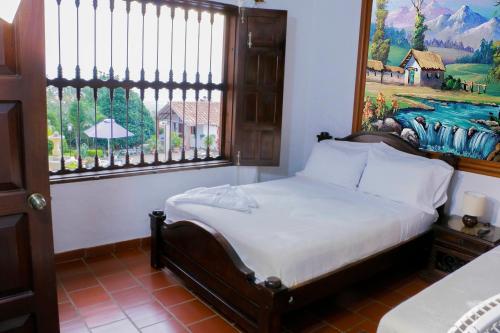 1 dormitorio con 1 cama con una pintura en la pared en Finca Villa Alicia, en Barichara
