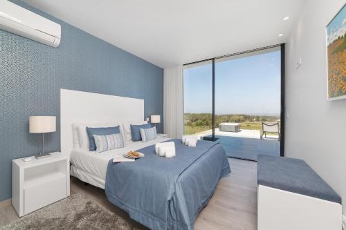 a bedroom with a large bed and a large window at Villa Natureza - By SCH in Serra do Bouro