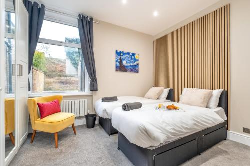 a bedroom with two beds and a yellow chair at Comfortable flat by MT Property in Nottingham