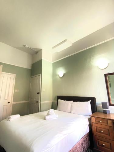 a bedroom with a large white bed and a wooden dresser at The Carlton Hotel in Folkestone