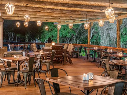 un restaurante con mesas y sillas de madera en una terraza de madera en Hazyview Cabanas, en Hazyview