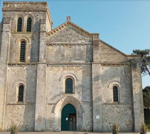 an old stone church with a green door at Villa centre-ville proche plage -6264 in Soulac-sur-Mer