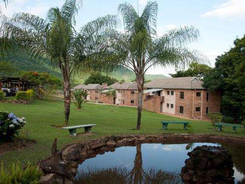 a park with a pond and trees and a building at Hazyview Cabanas in Hazyview