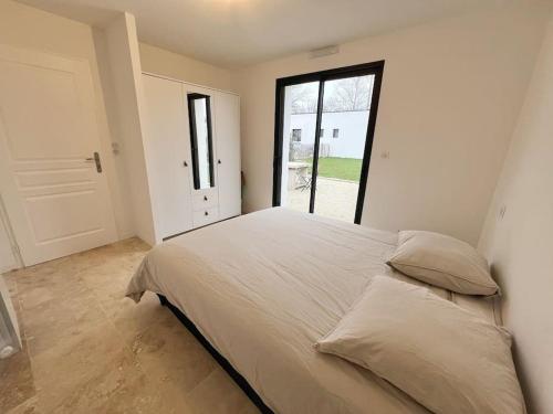 una camera da letto con un grande letto con una grande finestra di L'émeraude - Avec jardin a Lagord
