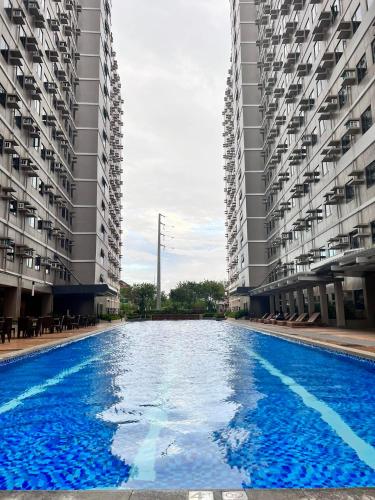 a large swimming pool between two tall buildings at SMDC Green 2 Staycation, The Traditional & Modern Fusion Condo in Pasong Bayog
