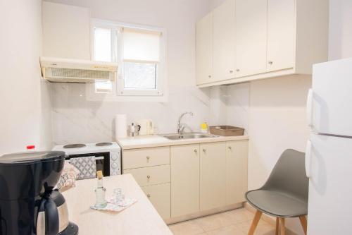 a small kitchen with white cabinets and a sink at Traveller's Nest Apartment close to center,port,airport in Heraklio Town