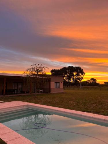 une piscine avec vue sur le coucher du soleil en arrière-plan dans l'établissement Quinta La Araucaria, à Norberto de la Riestra