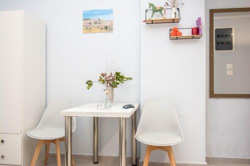 een tafel met twee stoelen en een vaas met bloemen erop bij Traveller's Nest Studio close to center,port,airport in Heraklion