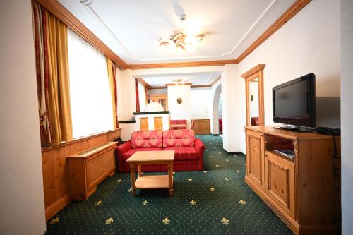 a hotel room with a red couch and a flat screen tv at Mercure Sighisoara Binderbubi Hotel & Spa in Sighişoara