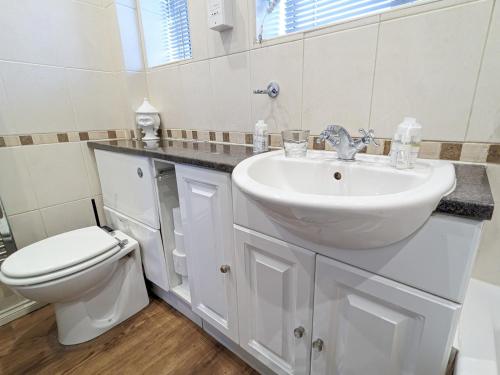 Baño blanco con lavabo y aseo en Epping Haven with Garden Oasis Pass The Keys, en Loughton