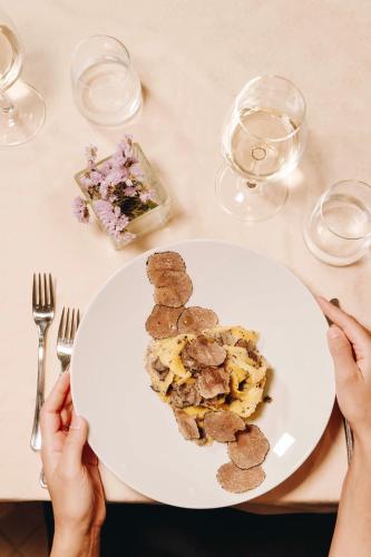 a person sitting at a table with a plate of food at Hotel Le Grotte in Genga