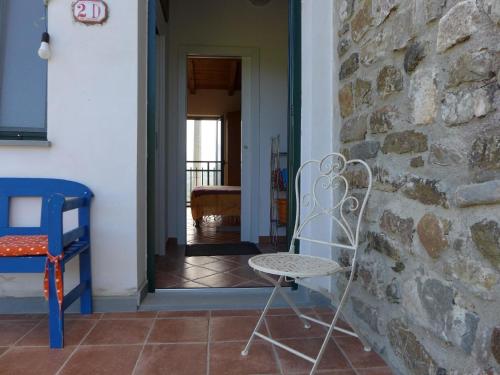 una silla blanca sentada junto a una pared de piedra en Mini-Appartement Casa Colombana mit Panoramablick, en Aulla