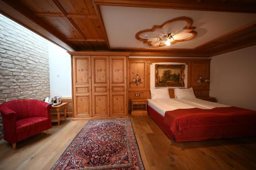 a bedroom with a bed and a red chair at Mercure Sighisoara Binderbubi Hotel & Spa in Sighişoara