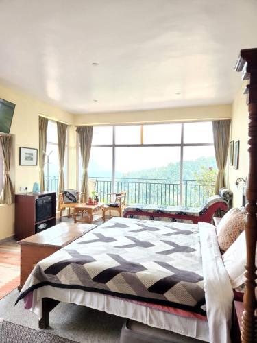 a bedroom with a bed and a large window at Cloudwalks Homestay in Kodaikānāl