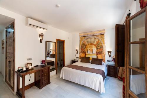 a bedroom with a bed and a desk and a mirror at Hotel Casa Museo de la Mezquita in Córdoba