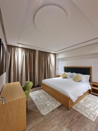 a bedroom with a large white bed and a table at Hotel Residence Ramsis in Nador