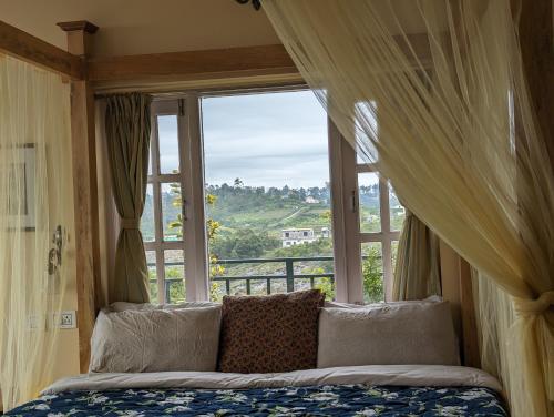 a bedroom with a bed and a large window at Cloudwalks Homestay in Kodaikānāl