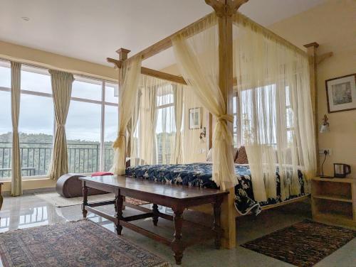 a bedroom with a canopy bed and a table at Cloudwalks Homestay in Kodaikānāl