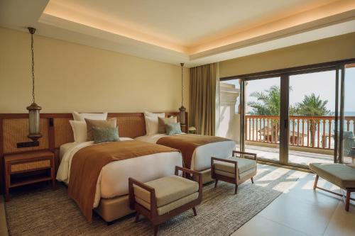 a bedroom with a large bed and a balcony at Naama Beach Villas & Spa in Al Aqah