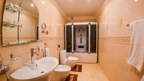 La salle de bains est pourvue d'un lavabo, de toilettes et d'une douche. dans l'établissement Reikartz Dostar Karaganda, à Karaganda