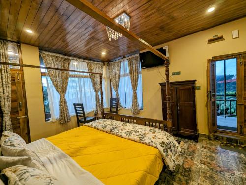 a bedroom with a yellow bed in a room with windows at Cloudwalks Homestay in Kodaikānāl