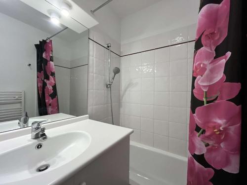 La salle de bains est pourvue d'un lavabo et d'un rideau de douche avec des fleurs roses. dans l'établissement Appart T2 Piscine Clim Parking - Gruissan - FR-1-229-548, à Gruissan